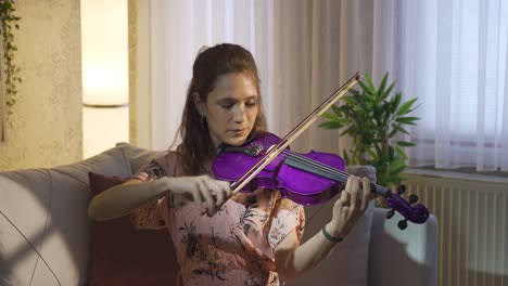 Musician-woman-playing-violin-alone-at-home.-Music-and-sheet-music.